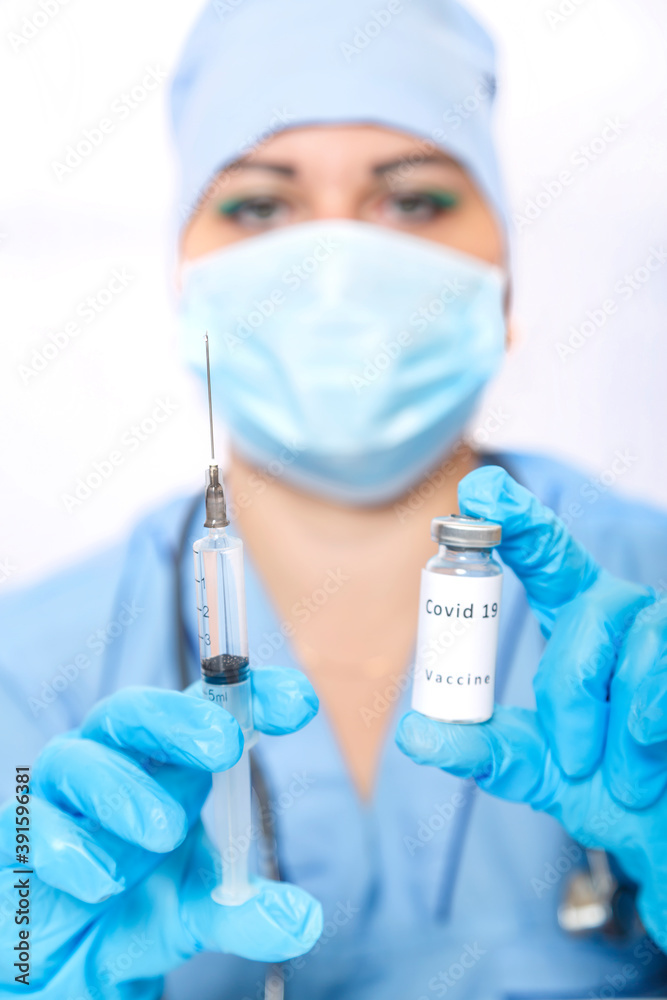 A vial with a vaccine against the virus and a syringe in the hands of a masked doctor. A vial with a vaccine against the virus and a syringe in the hands of a masked doctor.