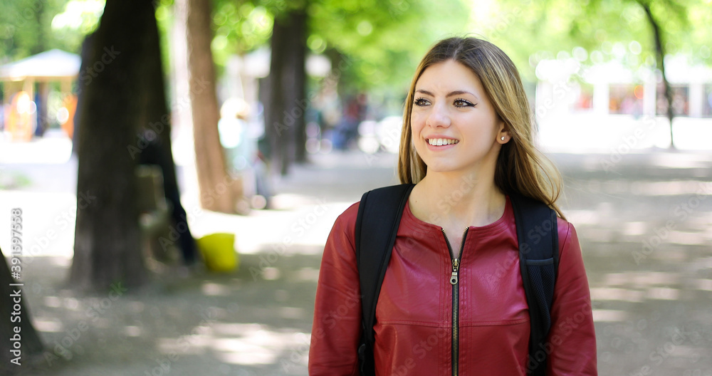 Female student walking outdoor in the park and smiling Female student walking outdoor in the park and smiling