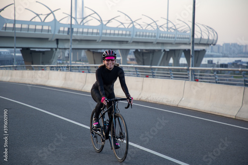 View of a girl exercising on a bicycle in the city in the morning at dawn. St. Petersburg Krestovsky Island Yakhtenny Bridge.