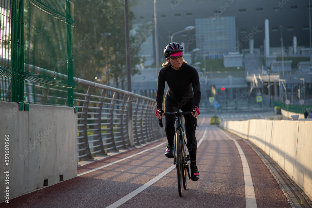 Obraz premium Morning exercise of a woman on a bike in the city. Outdoor sports. Krestovsky Island Saint Petersburg Russia.
