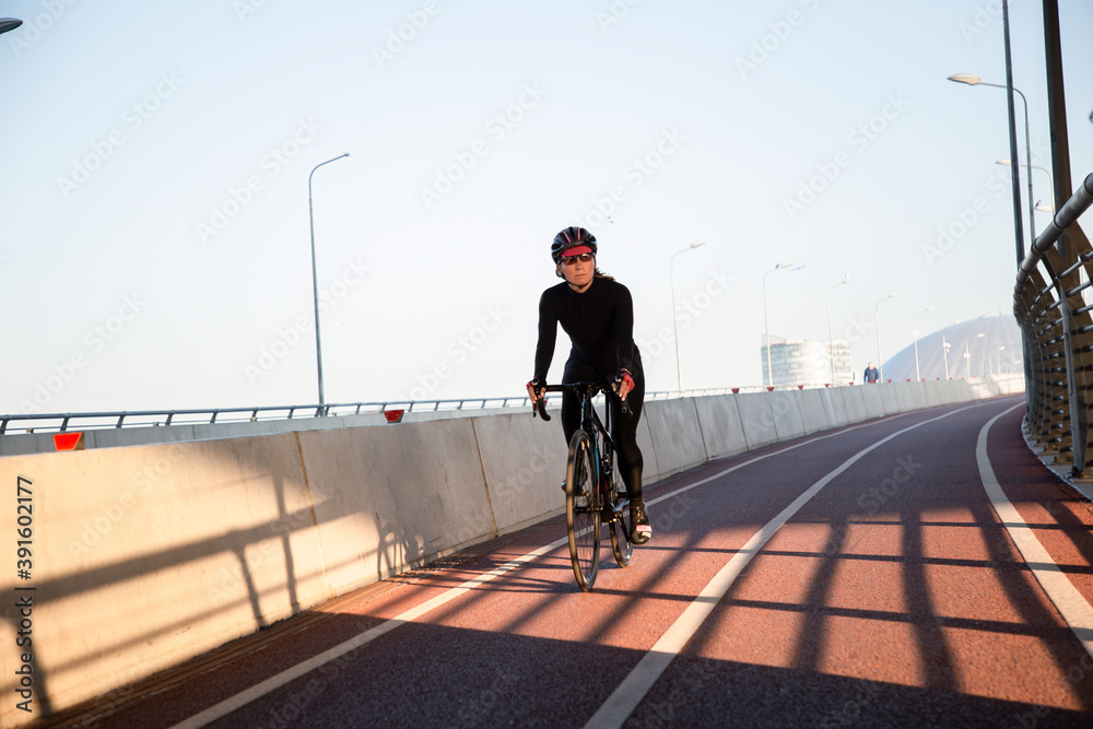 The girl rides a bicycle over the bridge. Morning workout in the city on a bike. Krestovsky Island St. Petersburg.