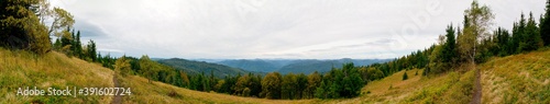 Beautiful autumn panorama of yellow and red trees against the background of big mountains