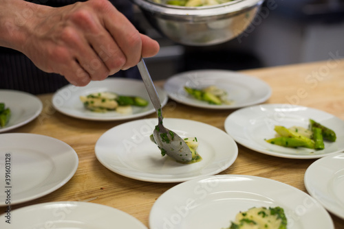 Plating slices of white and green asparagus on small plates as starter dish