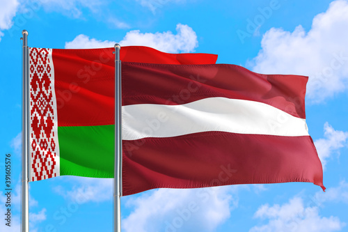 Latvia and Belarus national flag waving in the windy deep blue sky. Diplomacy and international relations concept.