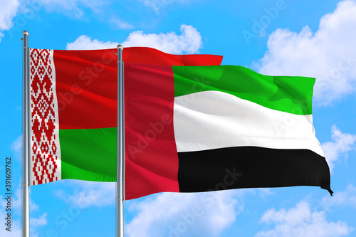 United Arab Emirates and Belarus national flag waving in the windy deep blue sky. Diplomacy and international relations concept.
