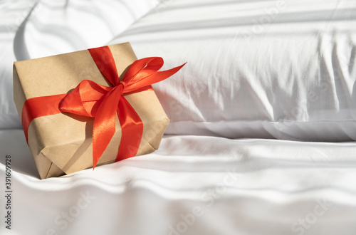 Christmas gift on bed with white bedding. sunny morning with shadow. © Юля Шевцова