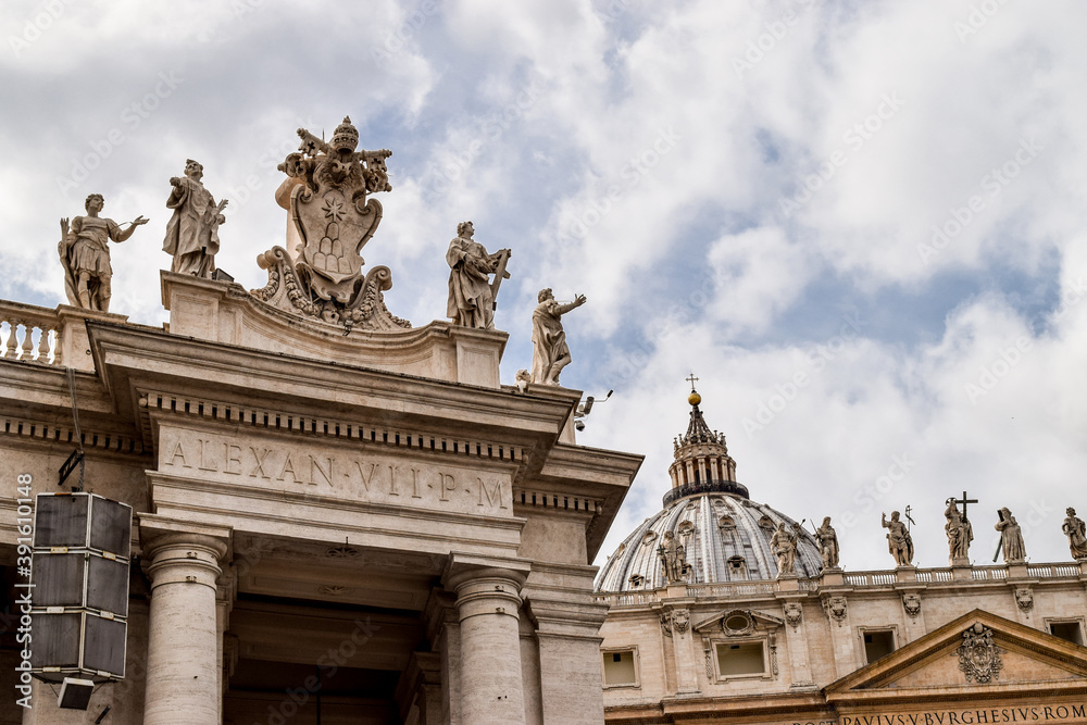 Close-up of architectural details of Saint Peter's Basilica and some of the statues on the doric columns that surround Saint Peter's Square. Vatican, Rome, Italy.