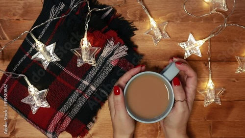 a woman warms her hands on a mug of hot chocolate