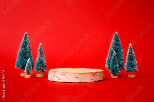 Mock up with wooden podium from a circle of wood on trendy red background with christmas decoration tree. Place for christmas product presentation