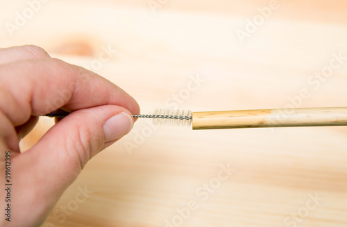Close up view of person using drinking straw cleaner brush to clean reusable bamboo drinking straw.