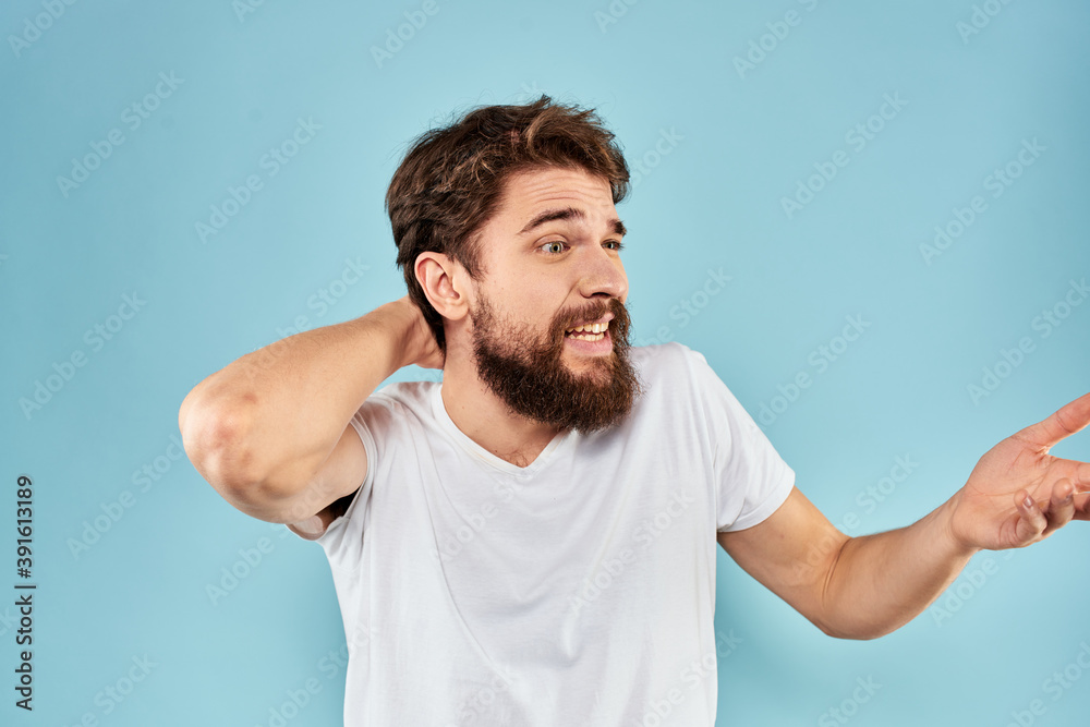 Emotional man with a beard in a white t-shirt blue background fun lifestyle Emotional man with a beard in a white t-shirt blue background fun lifestyle