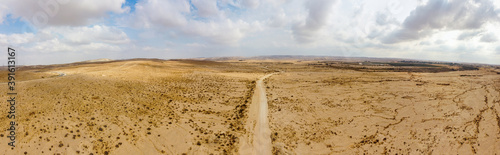 Wide panoramic view from the sky to dirt road over desert Negew