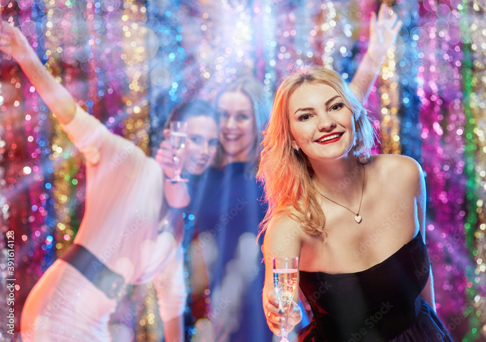 Fototapeta premium Portrait of cheerful friends celebrating New Year with drinks in hands