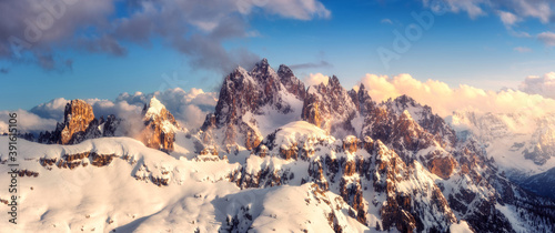Valokuva Snowy mountains in low clouds and blue sky at sunset in winter