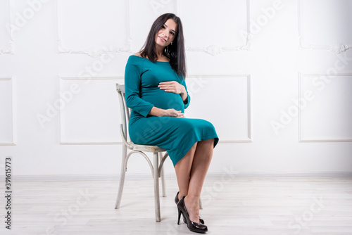 Pregnant girl in a green dress. In late pregnancy.