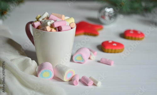 Cup with marshmallows and gingerbread. Christmas balls are blurred.