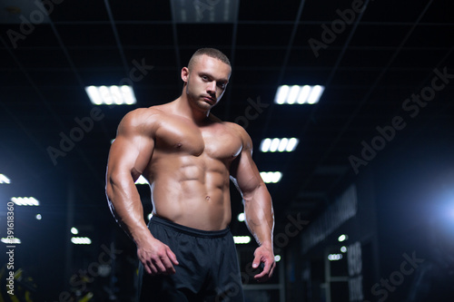 Sexy muscular sportsman is standing in a gym relaxing before workout