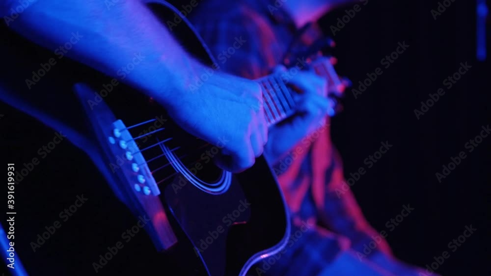 Two hipster men recording an indie song in the studio in neon lighting