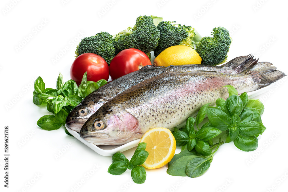 Raw fresh rainbow trout with assortment vegetables and lemons Raw fresh rainbow trout with assortment vegetables and lemons