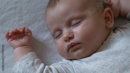 Close up video of a small newborn girl sleeping on a white blanket in the bedrrom while somebody is filming her photo