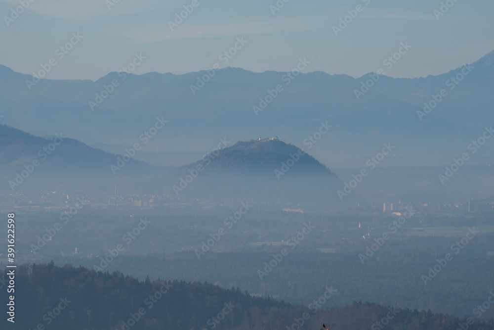 mystical and romantic mountain scenery with hilltops softly peaking out of white clouds. Fog flowing through the valleys. Layers of mountains in a beautiful landscape with the alps in the background 