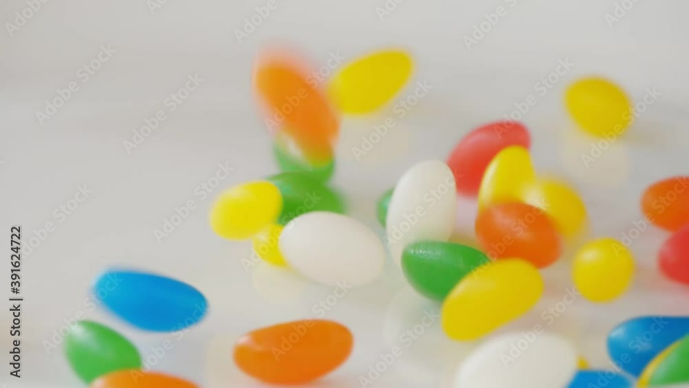 Multicolor Jelly Beans Candy Falls on White Background. Bright Tasty Colourful Texture Of Blue, Green, Yellow, Red, Orange and White Sweets in Slow Motion Multicolor Jelly Beans Candy Falls on White Background. Bright Tasty Colourful Texture Of Blue, Green, Yellow, Red, Orange and White Sweets in Slow Motion