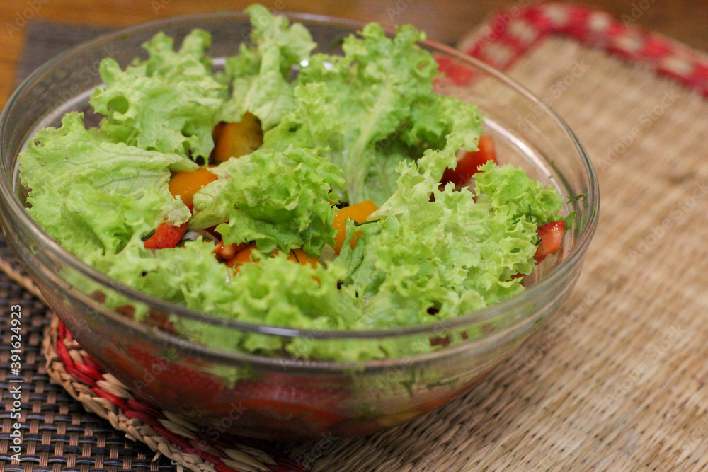 Delicious fresh vegetable salad in a glass plate standing on a bamboo stand Delicious fresh vegetable salad in a glass plate standing on a bamboo stand