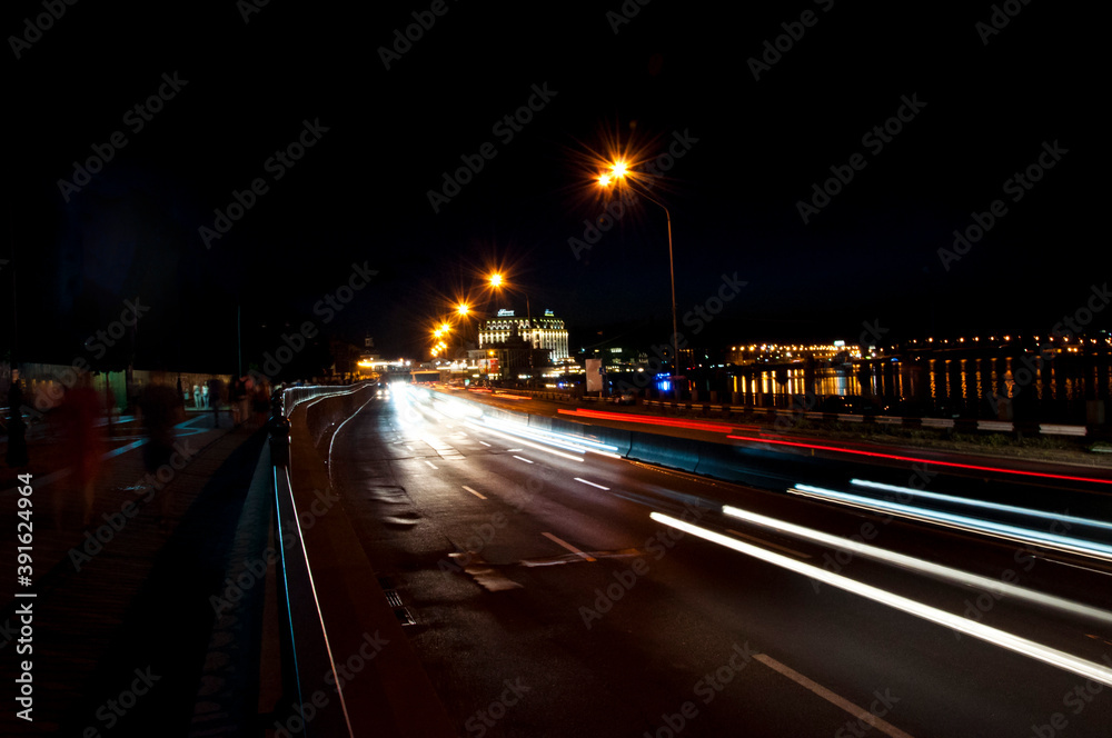 light trails on the modern city background. futuristic urban building with light trails. Light trails at night in urban environment. Road leading to modern illuminated night city. forward
