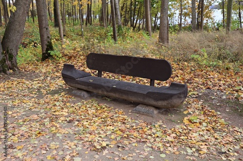 Tableau sur toile Bench similar to a small boat made of a tree trunk is installed in the park amon