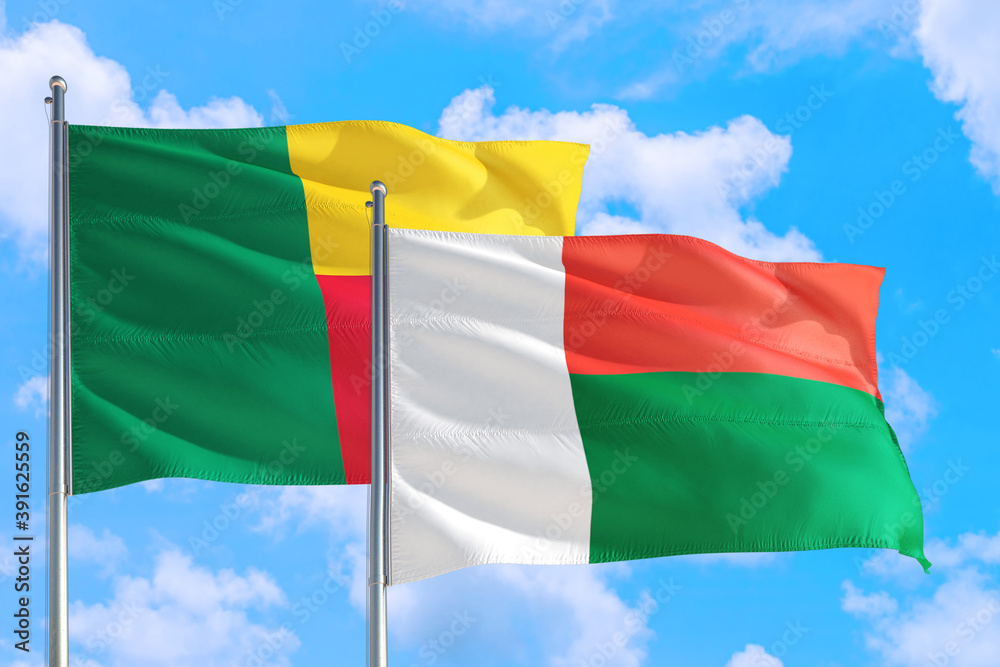 Obraz premium Madagascar and Benin national flag waving in the windy deep blue sky. Diplomacy and international relations concept.