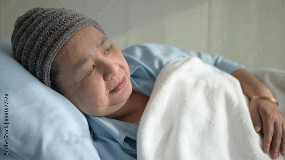 Depressed and hopeless Asian cancer patient woman wearing head scarf in hospital...
