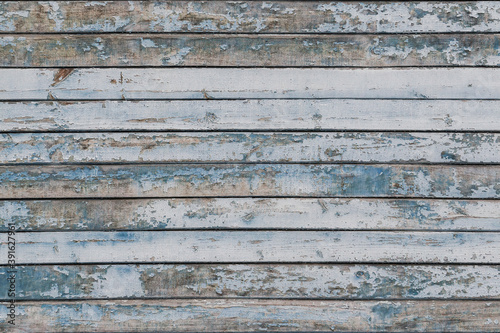 Full frame image of the weathered wooden wall with exfoliated light blue paint. Horizontal texture of old painted wood for wallpaper or background. Empty template for design, copy space