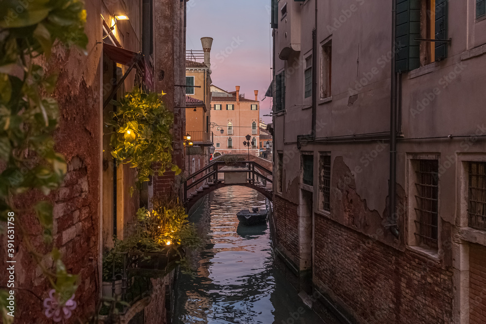 View at sunset of a small and picturesque Venice canal crossed by a bridge. Concept: Venetian atmosphere