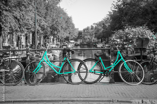 Two fresh azure bikes on the streets of Amsterdam. Symbol for clean and ecological urban transport. Isolated in a black and white background.