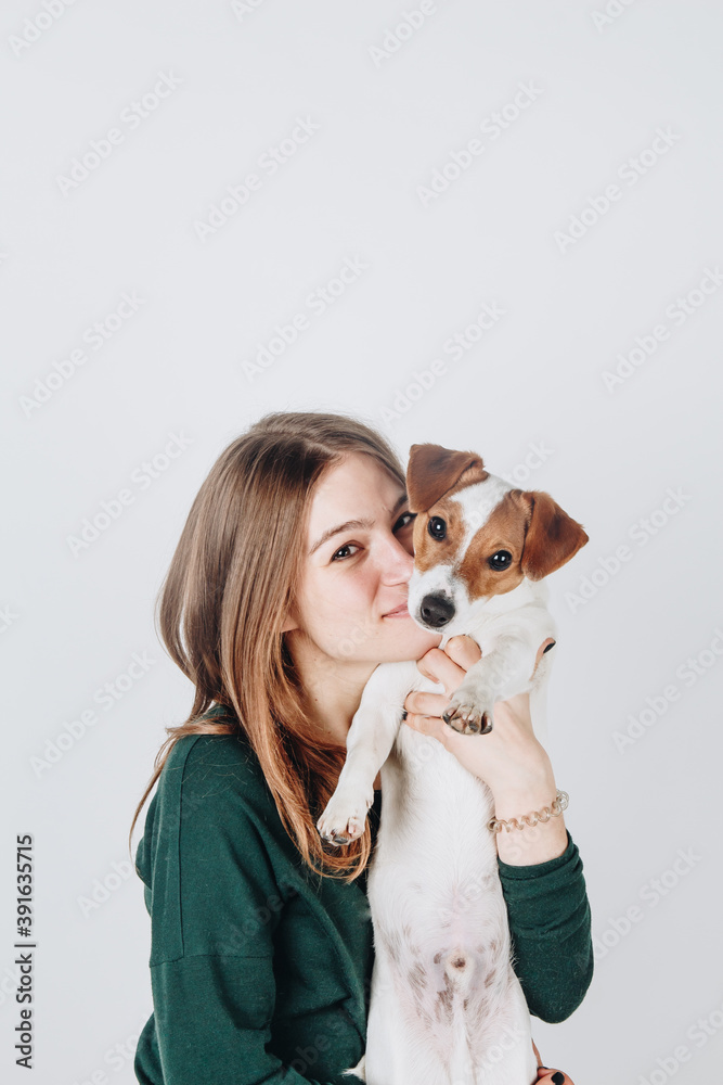Cute young woman kisses and hugs her puppy jack russell terrier dog. Love between owner and dog. Isolated on white background. Studio portrait. Cute young woman kisses and hugs her puppy jack russell terrier dog. Love between owner and dog. Isolated on white background. Studio portrait.