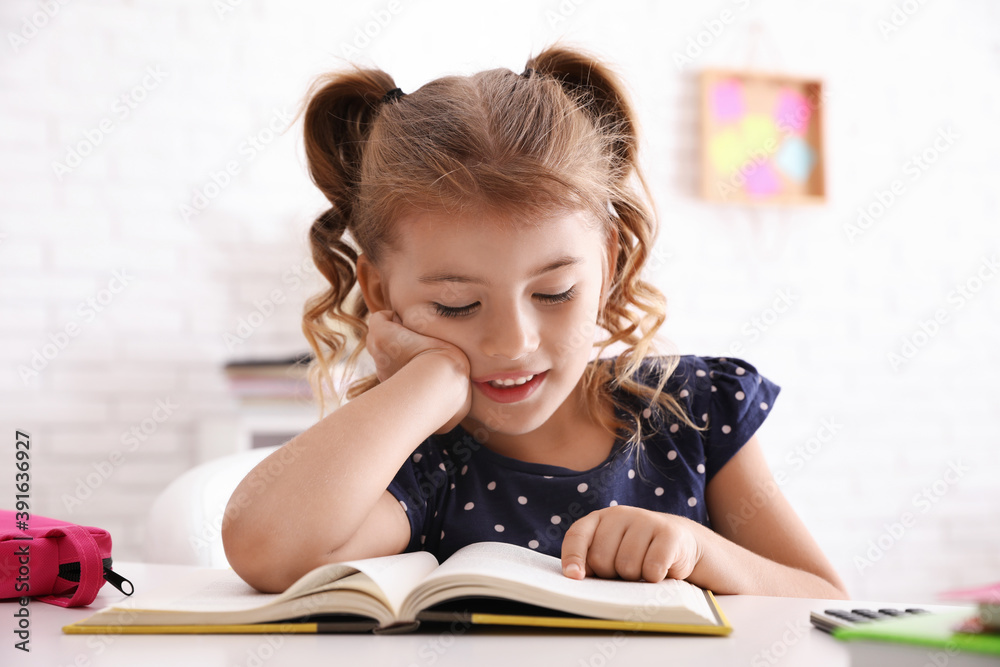 Cute little girl with book doing homework at table Cute little girl with book doing homework at table