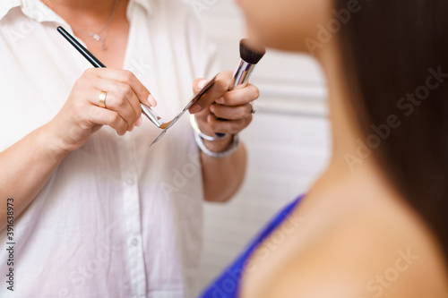 Professional makeup artist working with client in dressing room