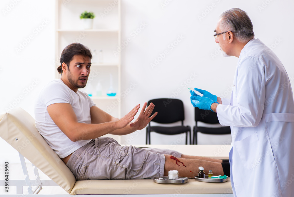 Leg injured man visiting old doctor in first aid concept Leg injured man visiting old doctor in first aid concept
