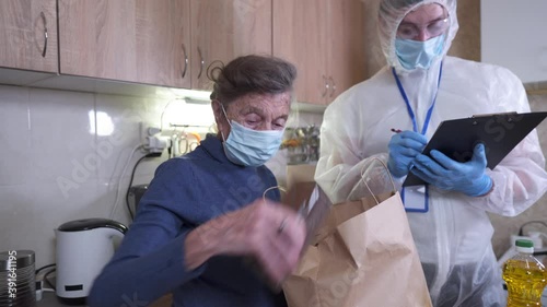 Man with bacteriological protection suit and protective mask delivering food to senior citizens in quarantine during Covid-19 Coronavirus epidemic. Donation box with foods, meals. Quarantine concept