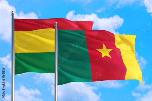 Cameroon and Bolivia national flag waving in the windy deep blue sky. Diplomacy and international relations concept.