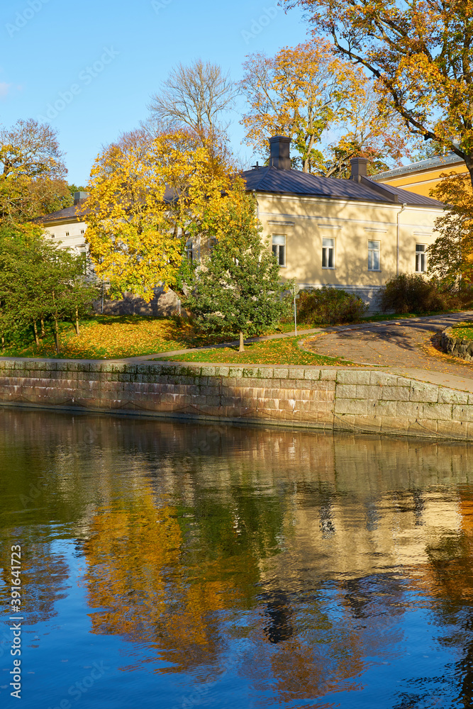 Autumn on Aura river in Turku, Finland. Reflections of house, trees and sky on water.