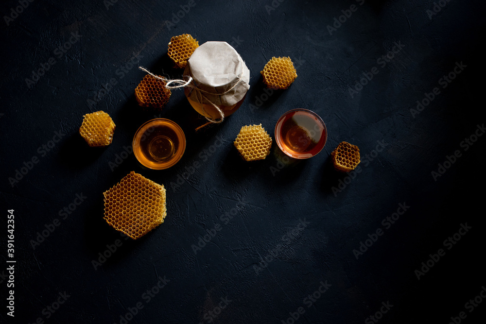 Honey in a jar and a honeycomb. On a black wooden background. Free space for text. Top view.