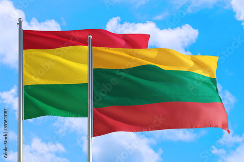 Lithuania and Bolivia national flag waving in the windy deep blue sky. Diplomacy and international relations concept.