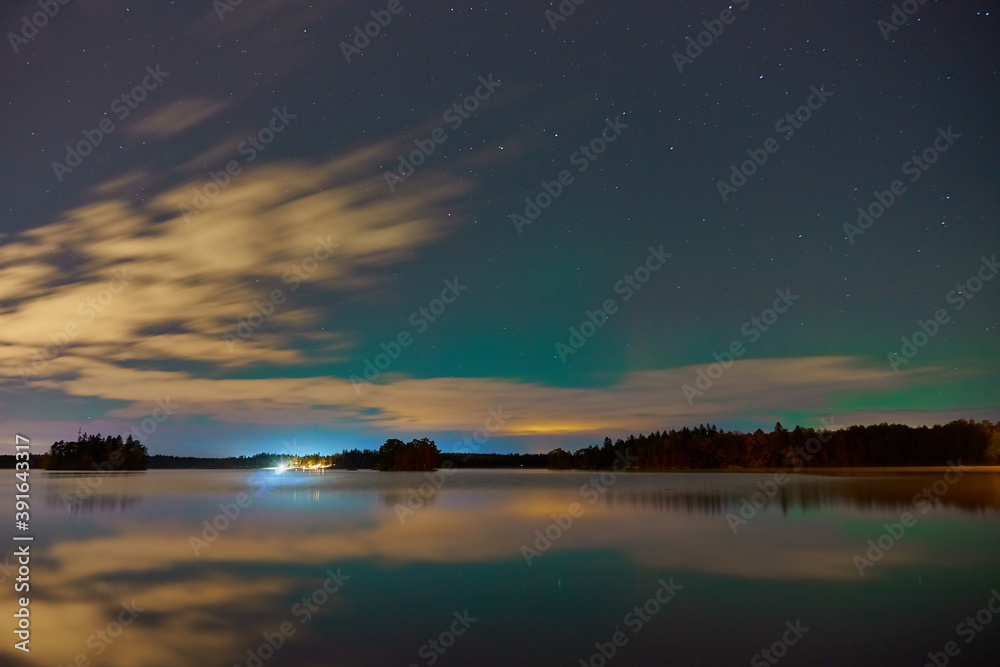 Aurora borealis Northern lights behind the clouds on Littoinen lake, Finland with reflections on water. Aurora borealis Northern lights behind the clouds on Littoinen lake, Finland with reflections on water.