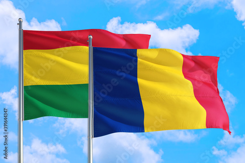 Romania and Bolivia national flag waving in the windy deep blue sky. Diplomacy and international relations concept.