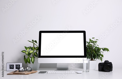 Comfortable workplace with modern computer on table near white wall. Space for text