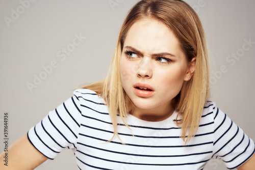 Emotional blonde woman in striped t-shirt lifestyle facial expression close-up