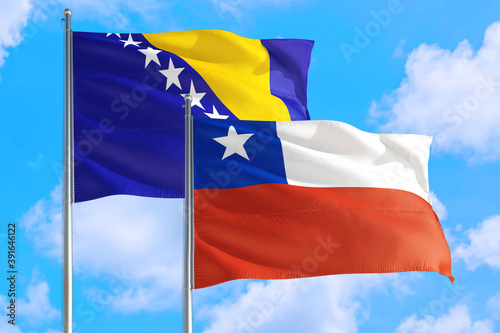 Chile and Bosnia Herzegovina national flag waving in the windy deep blue sky. Diplomacy and international relations concept.