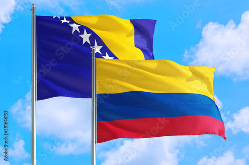Colombia and Bosnia Herzegovina national flag waving in the windy deep blue sky. Diplomacy and international relations concept.
