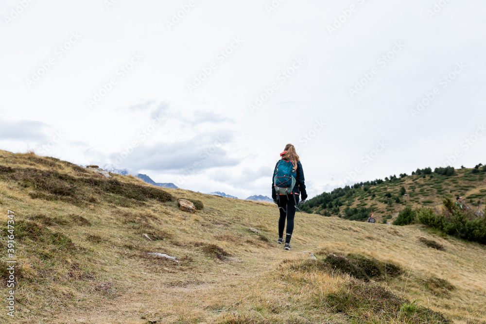 Blonde teenager walking in the mountains in winter in Pyrenees during Ibon de Piedrafita route